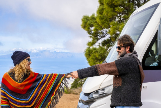 Romantischer Moment auf Reisen: Ein Paar begrüßt sich vor ihrem Camper.