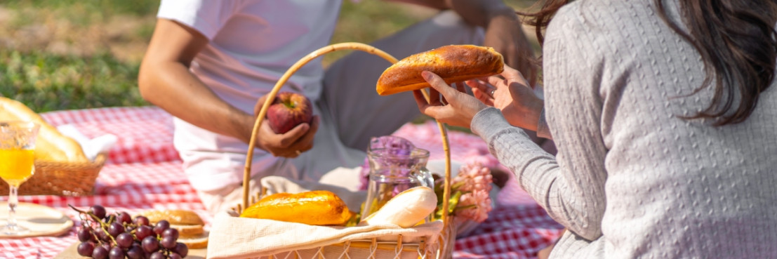 Ein Paar picknickt mit frischen Broten und Obst auf einer Decke während einer Camperreise durch Rivierenland.