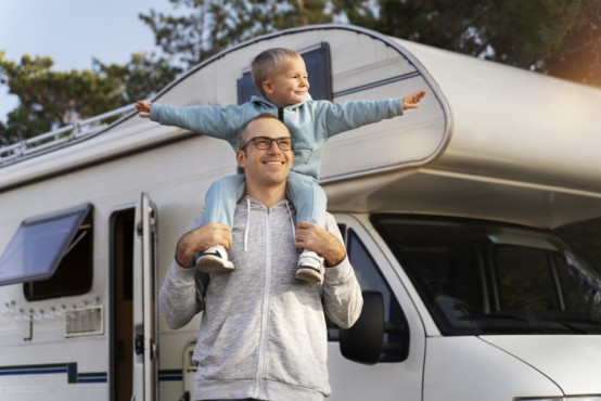 Ein Mann mit Kind macht einen Zwischenstopp mit dem Camper, um die Aussicht zu genießen.